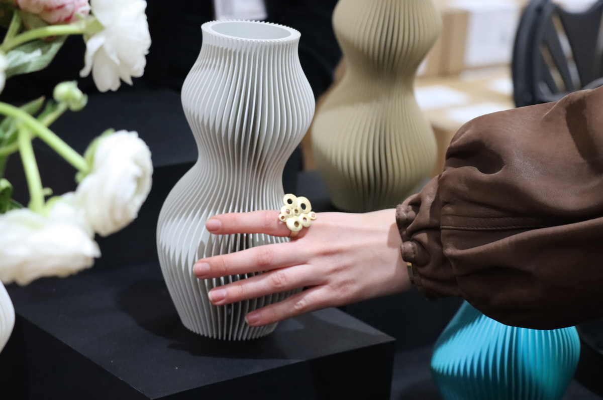 A hand resting on a white Breeze Vase, showing the ribbed 3D printed texture up close